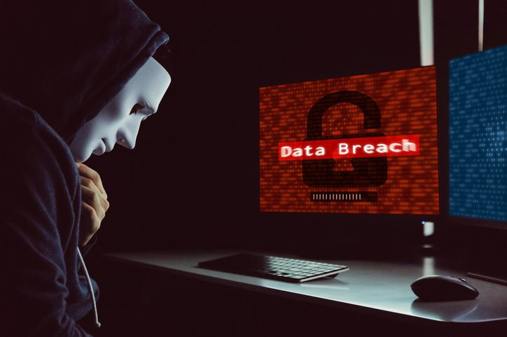 Masked hacker under hood using computer to commit data breach crime - internet computer crime concept. Masked hacker under hood using computer to commit data breach crime - internet computer crime concept